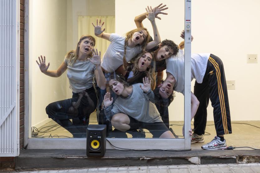 The image shows several people pressing themselves against the glass of a store, with their faces and limbs sticking to the glass.