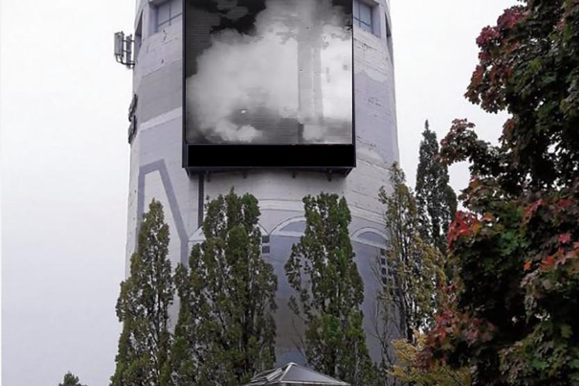 The image shows the Robert Bosch Tower, which features a large screen area. On this screen, smoke clouds from a fog machine are visible.